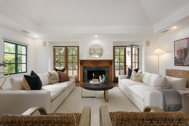 living room featuring a wealth of natural light, french doors, a high end fireplace, and lofted ceiling