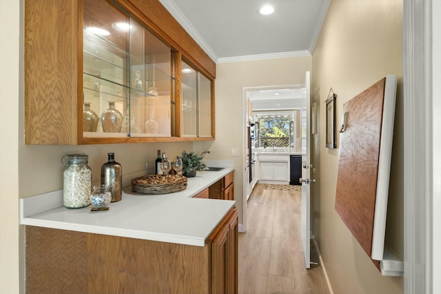 bar with dishwasher, light hardwood / wood-style floors, ornamental molding, and sink