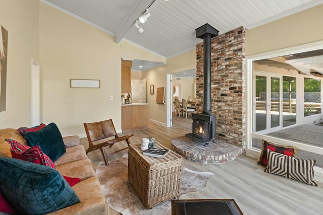 living room with a wood stove, hardwood / wood-style floors, lofted ceiling with beams, and track lighting