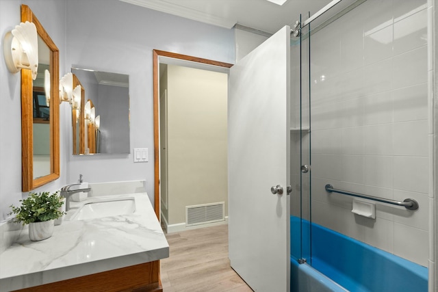 bathroom with combined bath / shower with glass door, vanity, hardwood / wood-style flooring, and ornamental molding