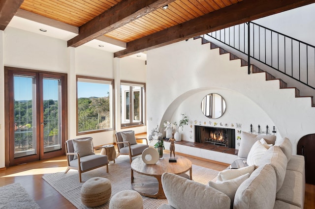 living room with a fireplace, wood ceiling, beam ceiling, and light hardwood / wood-style flooring