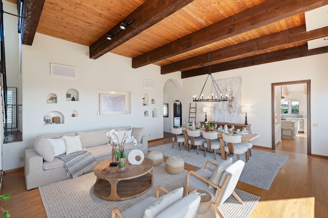 living room with track lighting, wood ceiling, a notable chandelier, light wood-type flooring, and beam ceiling