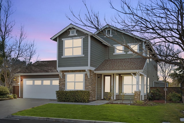 view of front of home with a garage, a shingled roof, driveway, a yard, and stone siding