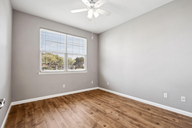 empty room featuring ceiling fan, baseboards, and wood finished floors