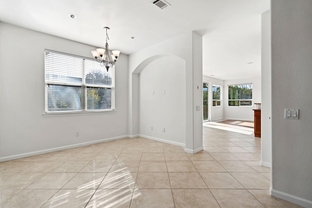 empty room with arched walkways, visible vents, an inviting chandelier, light tile patterned flooring, and baseboards