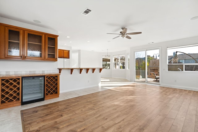 unfurnished living room with recessed lighting, beverage cooler, visible vents, baseboards, and light wood-type flooring