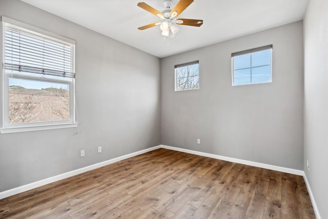 empty room featuring a ceiling fan, baseboards, and wood finished floors