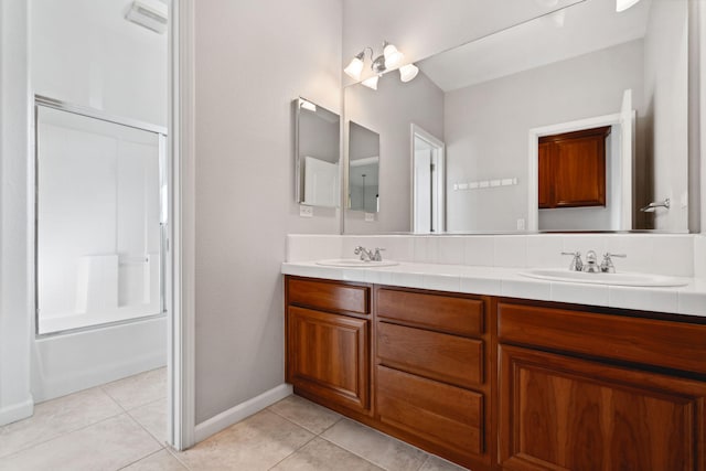 bathroom with bath / shower combo with glass door, a sink, and tile patterned floors