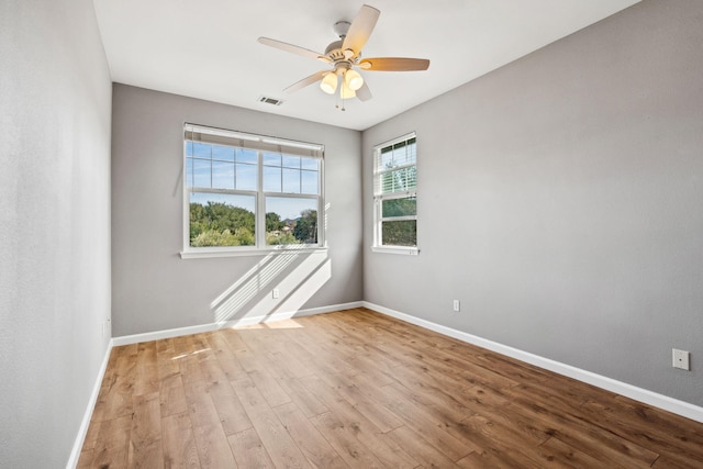 spare room featuring light wood-type flooring, visible vents, ceiling fan, and baseboards