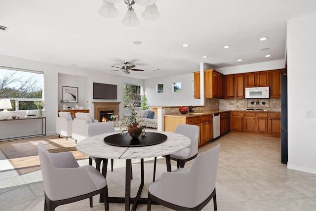 dining space with light tile patterned floors, recessed lighting, visible vents, ceiling fan, and a warm lit fireplace