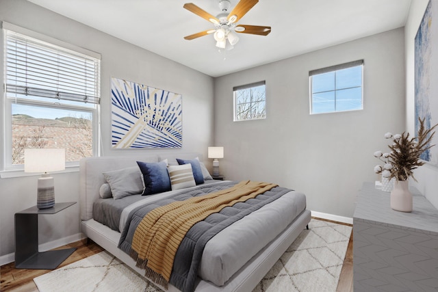 bedroom featuring wood finished floors, a ceiling fan, and baseboards