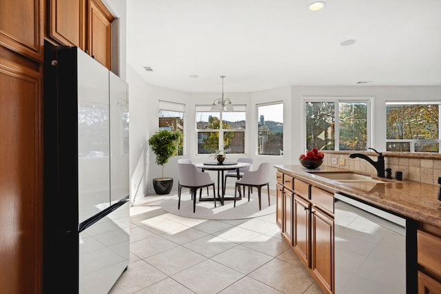 kitchen featuring pendant lighting, tasteful backsplash, freestanding refrigerator, a sink, and dishwasher