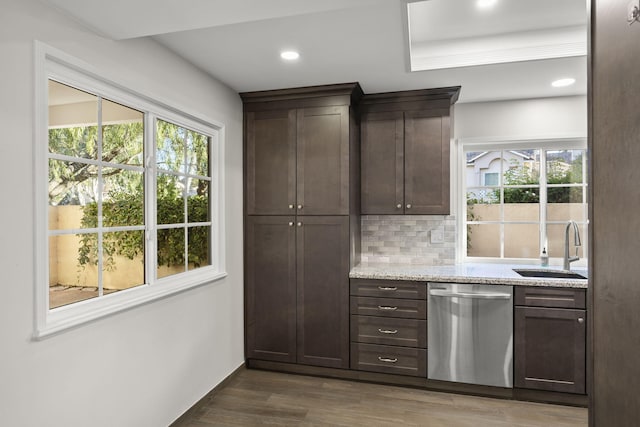 kitchen featuring dishwasher, sink, dark wood-type flooring, light stone counters, and backsplash