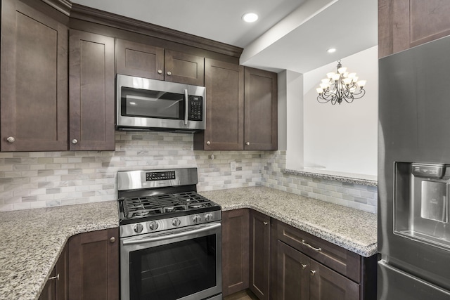 kitchen with tasteful backsplash, light stone countertops, stainless steel appliances, and an inviting chandelier