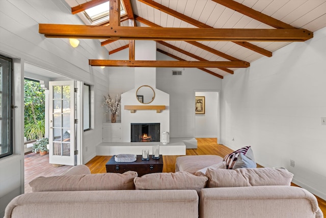 living room with beamed ceiling, a fireplace, high vaulted ceiling, and light hardwood / wood-style flooring