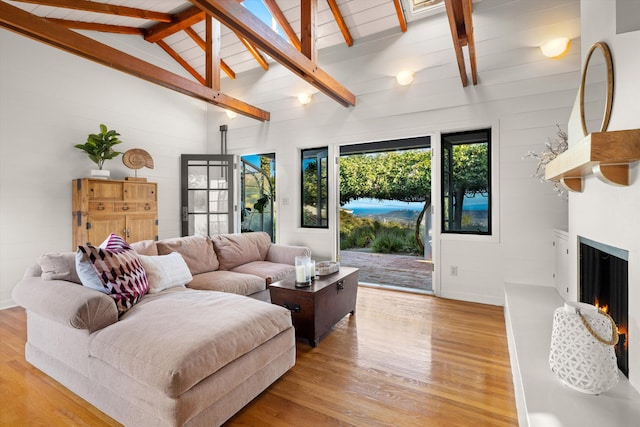 living room with beamed ceiling, light hardwood / wood-style floors, a fireplace, and high vaulted ceiling