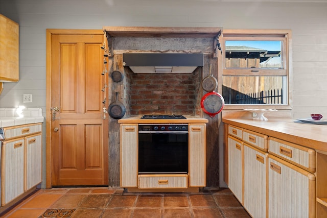 kitchen featuring wood walls, light brown cabinets, oven, and range hood