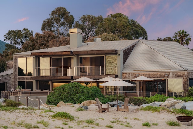 back house at dusk featuring a balcony