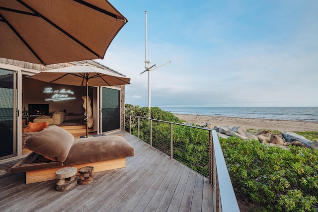 wooden terrace with a water view and a view of the beach