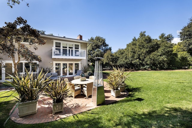 back of house featuring a lawn, a balcony, and a patio