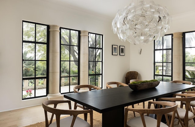 dining space with light hardwood / wood-style flooring, crown molding, and ornate columns