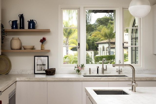 kitchen with white cabinets, light stone countertops, and sink