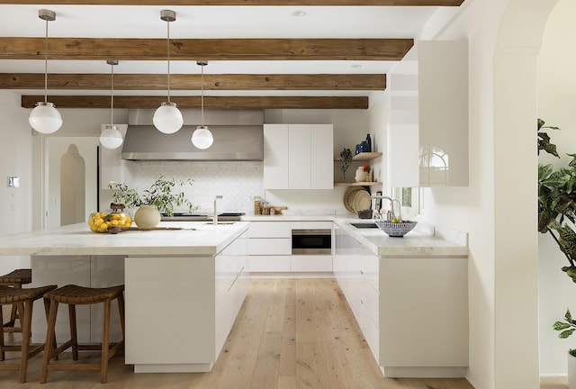 kitchen with beamed ceiling, decorative light fixtures, white cabinets, and backsplash