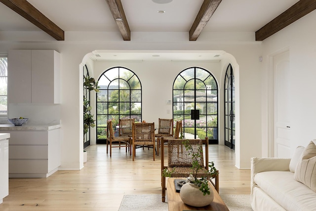 dining area with beamed ceiling and light wood-type flooring