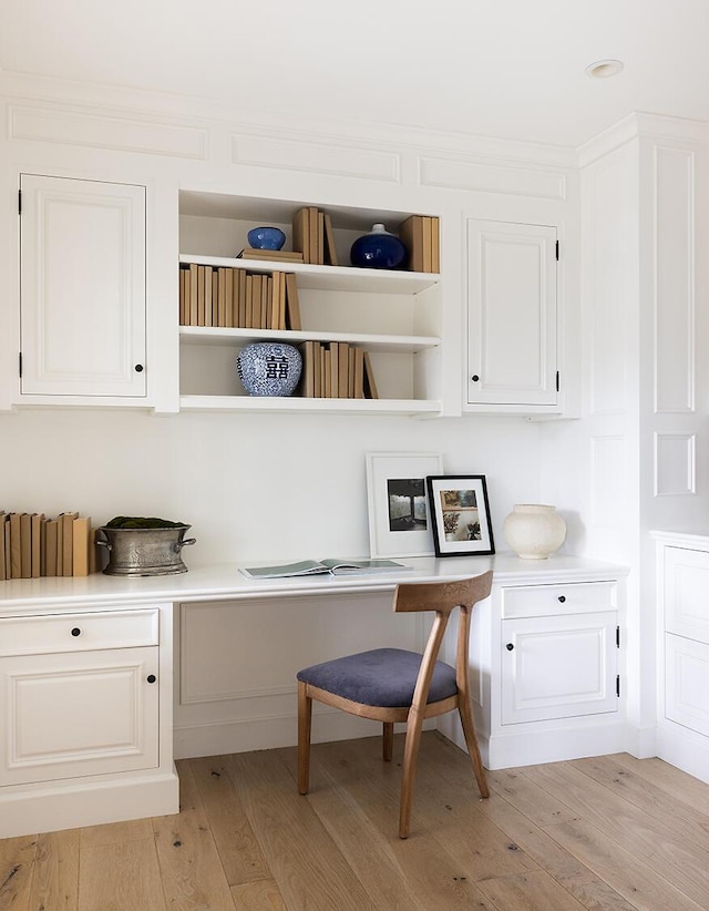 home office featuring light hardwood / wood-style floors and built in desk