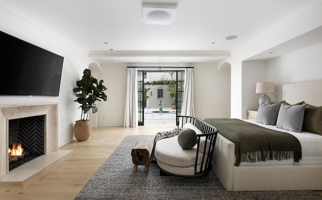 bedroom with crown molding, a fireplace, and light hardwood / wood-style flooring