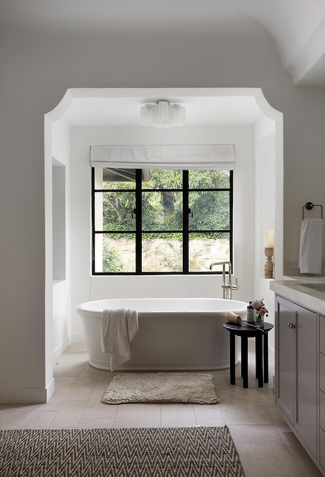 bathroom featuring tile patterned flooring, a bath, and a wealth of natural light