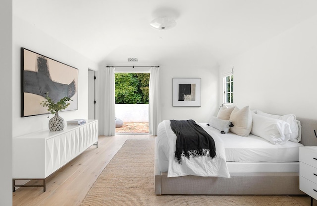 bedroom with lofted ceiling, light wood-type flooring, and access to outside