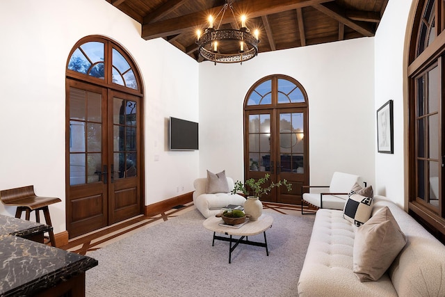 living room featuring beam ceiling, french doors, high vaulted ceiling, a notable chandelier, and wood ceiling