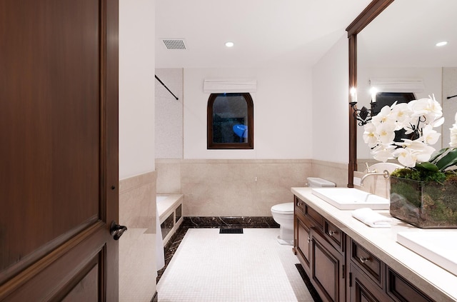 bathroom featuring tile patterned flooring, vanity, toilet, and tile walls