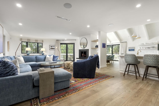 living room with vaulted ceiling with beams, light hardwood / wood-style floors, and sink