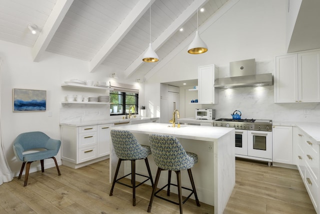 kitchen featuring tasteful backsplash, white cabinets, double oven range, and wall chimney range hood