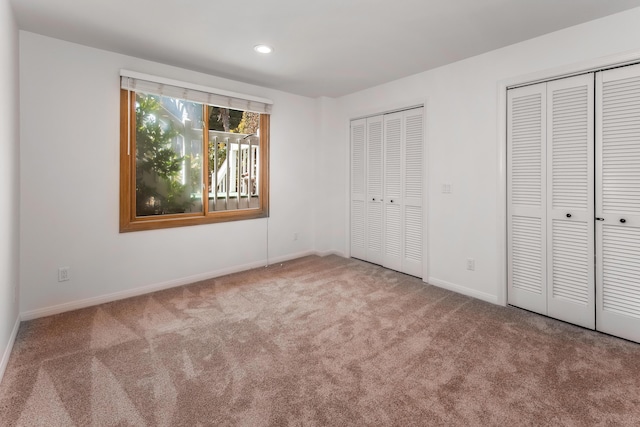 unfurnished bedroom featuring carpet and multiple closets