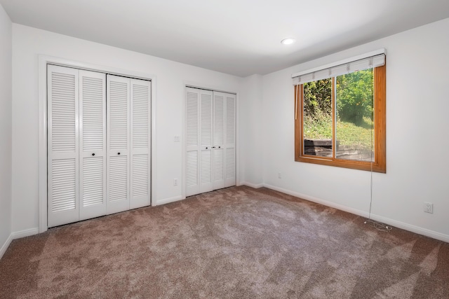 unfurnished bedroom with carpet floors and two closets