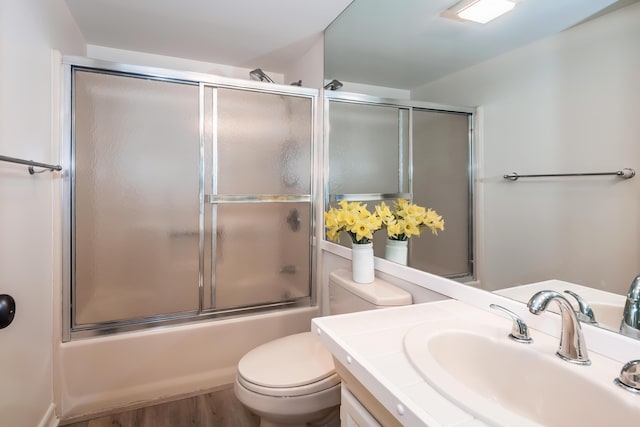 full bathroom with toilet, wood-type flooring, vanity, and shower / bath combination with glass door