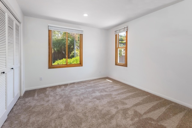 unfurnished bedroom with light colored carpet, multiple windows, and a closet