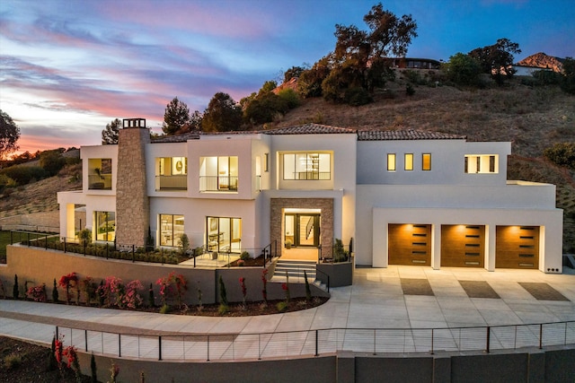 rear view of property with fence, concrete driveway, and stucco siding