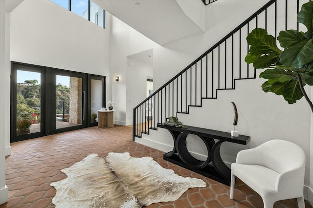 foyer with a towering ceiling, stairs, and baseboards