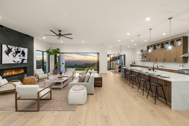 living room featuring light wood finished floors, ceiling fan, a fireplace, and recessed lighting