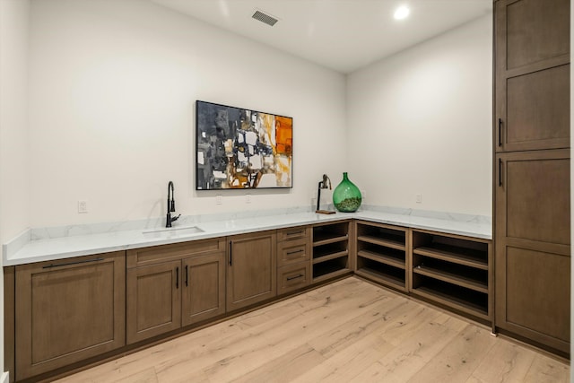 bar with bar area, visible vents, a sink, and light wood-style flooring