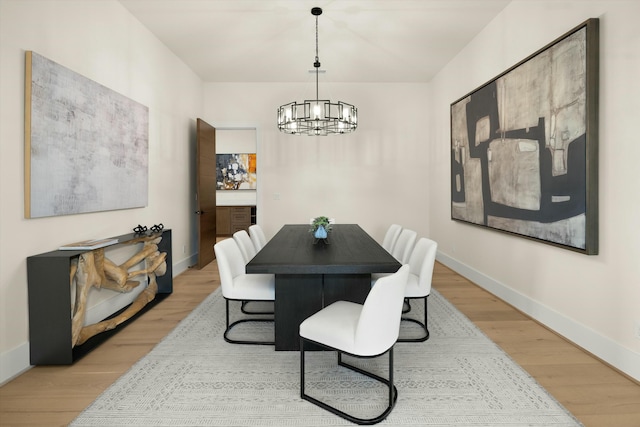 dining room featuring light wood-type flooring, baseboards, and a notable chandelier