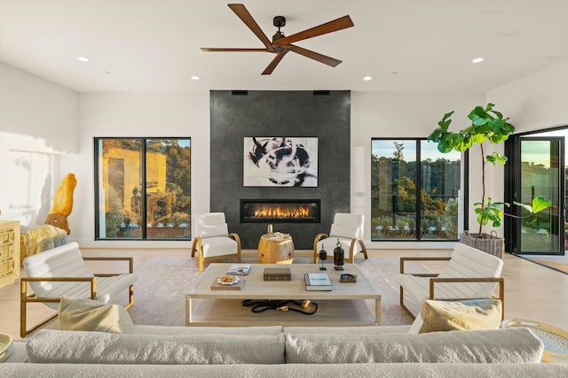 living area featuring a large fireplace, light wood-type flooring, a ceiling fan, and recessed lighting