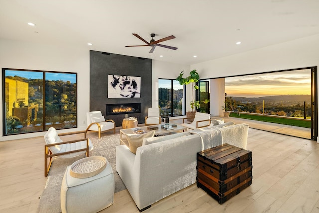 living room featuring a large fireplace, ceiling fan, light wood-style flooring, and recessed lighting