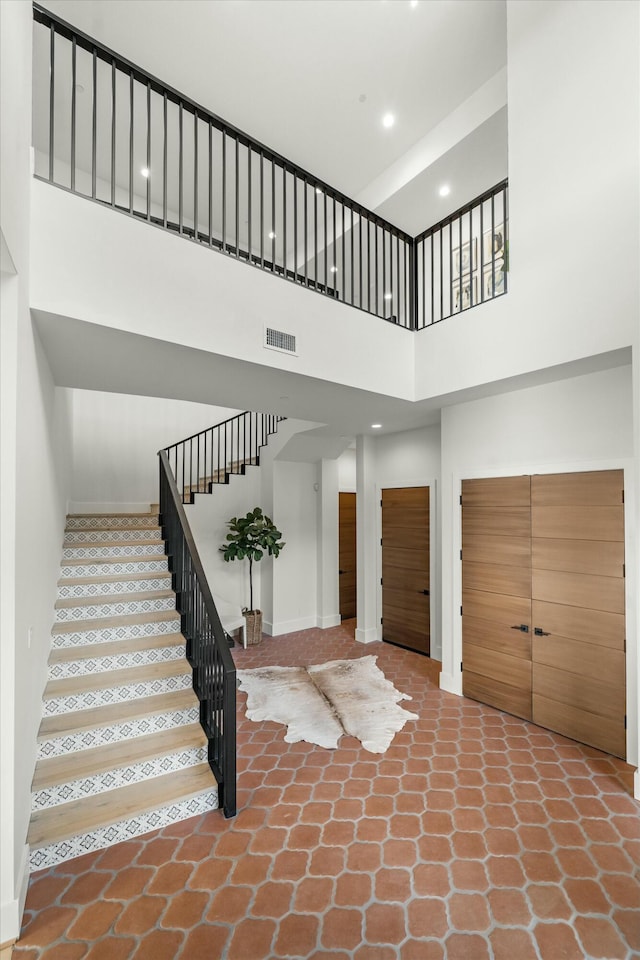 stairs featuring baseboards, a towering ceiling, visible vents, and recessed lighting