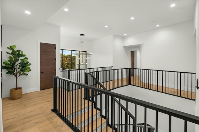 corridor with light wood-style floors, recessed lighting, baseboards, and an upstairs landing