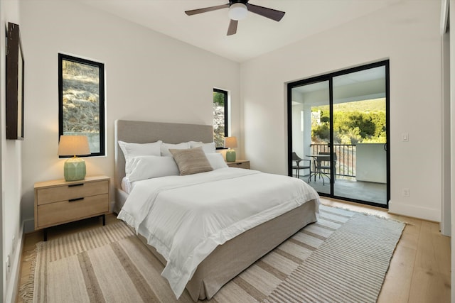 bedroom with light wood-type flooring, access to outside, multiple windows, and baseboards